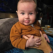 Enzo a rejoint le concours — aidez-le/la à gagner de superbes lots ! baby, child, infant, face, hands, sweater, couch, indoor, person, portrait, expression, holding, bubble, clothing, adult_hand, bracelet, cozy, cute, seated, soft_light