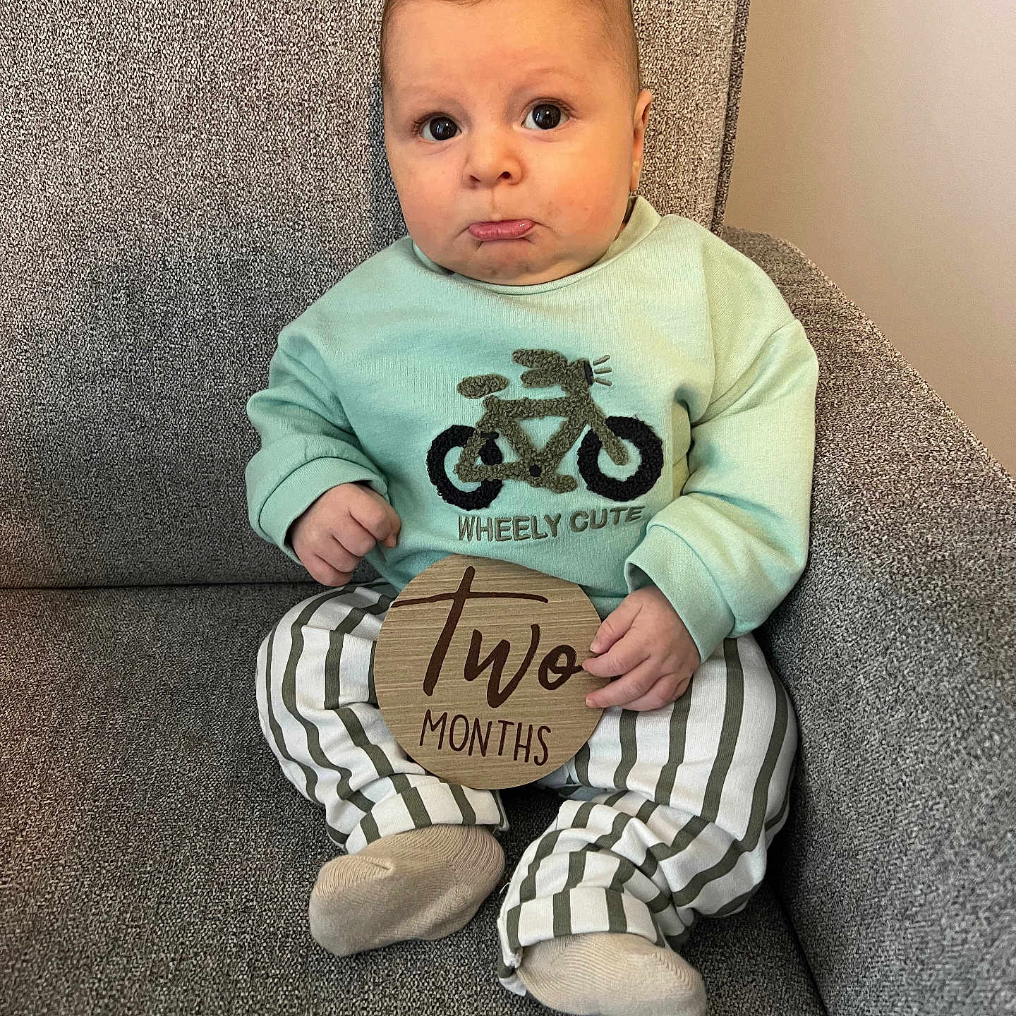 Liam is registered to the contest to win money with this photo: baby, clothing, couch, cushion, face, footwear, furniture, head, homedecor, hosiery, pants, person, photography, portrait, shoe, sitting, sleeve, sock, t_shirt, text