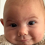 Leo participe au concours pour gagner de l'argent avec cette photo : baby, close_up, face, eyes, smile, infant, knitted_sweater, cute, portrait, skin, head, chubby_cheeks, expression, person, child, young, indoors, human, warm_clothing, cozy