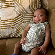Benjamin is registered to the contest to win money with this photo: baby, blue_socks, child, comfort, couch, cozy, cute, dinosaur_print, expression, happy, indoors, infant, leather, onesie, pillow, portrait, relax, seated, skin, smile