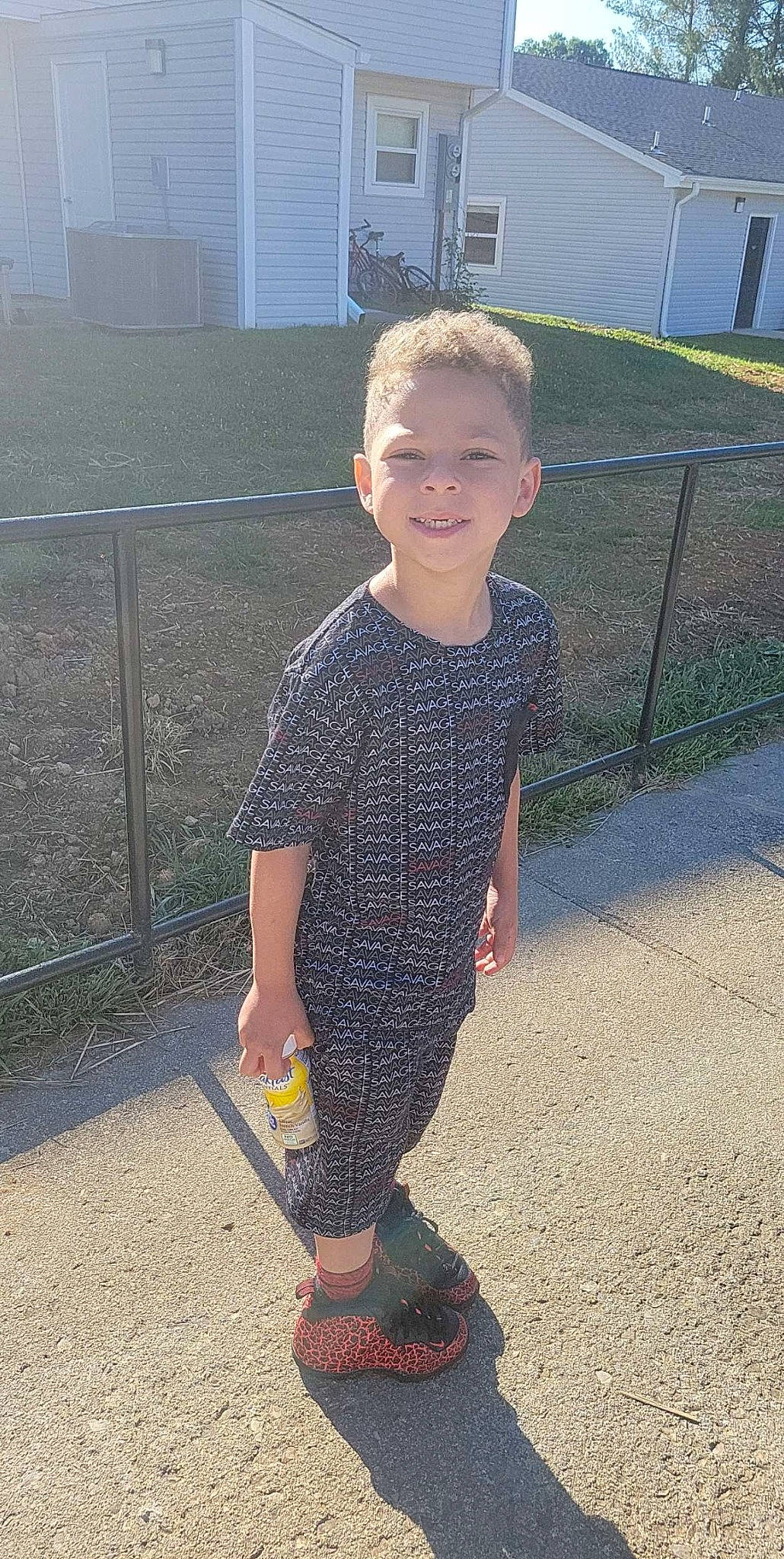 Camron is registered to the contest to win money with this photo: asphalt, child, cool, denim, fence, fun, grass, human_body, human_leg, joy, knee, outerwear, pajamas, pattern, person, recreation, sleeve, smile, t_shirt, thigh