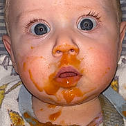 Carina joined the competition — help win amazing prizes! baby, messy_face, blue_eyes, puree, orange_sauce, bib, spilled_food, close_up, surprised_expression, drool, flash_photo, eyelashes, forehead, cheek, nose, mouth, hair, highchair_strap, baby_clothing, portrait