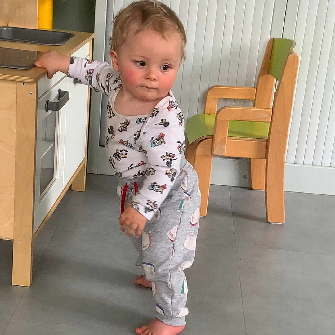 Lino a rejoint le concours — aidez-le/la à gagner de superbes lots ! barefoot, cabinet, child, contemplative, curious, floor, furniture, green_cushion, home, indoor, light_skin, long_sleeve_shirt, pants, play_kitchen, short_hair, standing, toddler, toy, wooden_chair, yellow_faucet