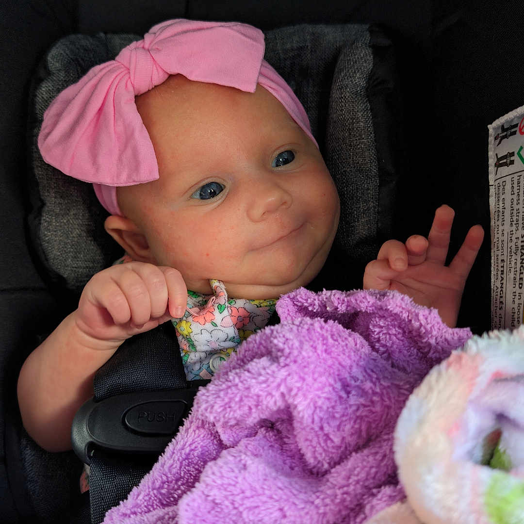 Sophie is registered to the contest to win money with this photo: baby, blanket, bodypart, bonnet, car, car_interior, carseat, clothing, face, finger, hand, hat, head, homedecor, person, photography, portrait, towel, transportation, vehicle