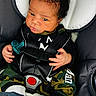 baby, infant, car_seat, pacifier, clothing, camo_pants, socks, seatbelt, child, person, face, hand, indoor, cute, expression, black_hair, safety, portrait, newborn, closeup