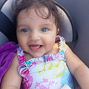 Lina a rejoint le concours — aidez-le/la à gagner de superbes lots ! baby, child, smiling, blue_eyes, curly_hair, colorful_clothing, seat, blanket, happy, infant, cute, portrait, ruffled_straps, cushion, indoors, skin, face, person, young_child, sitting