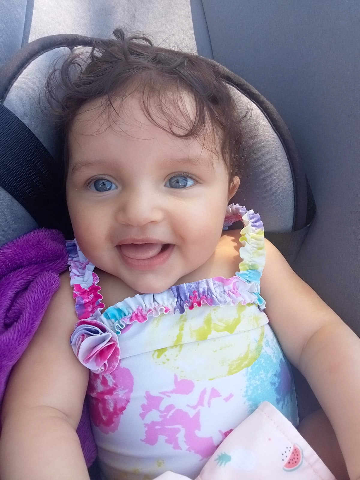 Lina a rejoint le concours — aidez-le/la à gagner de superbes lots ! baby, child, smiling, blue_eyes, curly_hair, colorful_clothing, seat, blanket, happy, infant, cute, portrait, ruffled_straps, cushion, indoors, skin, face, person, young_child, sitting