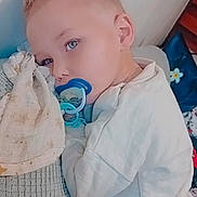 Mayron participe au concours pour gagner de l'argent avec cette photo : blanket, blond_hair, blue_eyes, child, close_up, comfort_item, couch, home_interior, indoor, lying_down, nursery, pacifier, pillow, portrait, relaxed, sleepy, soft_lighting, toddler, toy, white_clothing