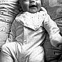 baby, smiling, onesie, bib, cushion, pattern, black_and_white, infant, happy, face, portrait, lying_down, cute, child, soft, cozy, clothing, baby_bedding, newborn, expression