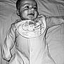 baby, infant, onesie, bib, smile, face, lying_down, bed, sleepwear, cute, child, monochrome, black_and_white, portrait, young, happy, skin, head, expression, person