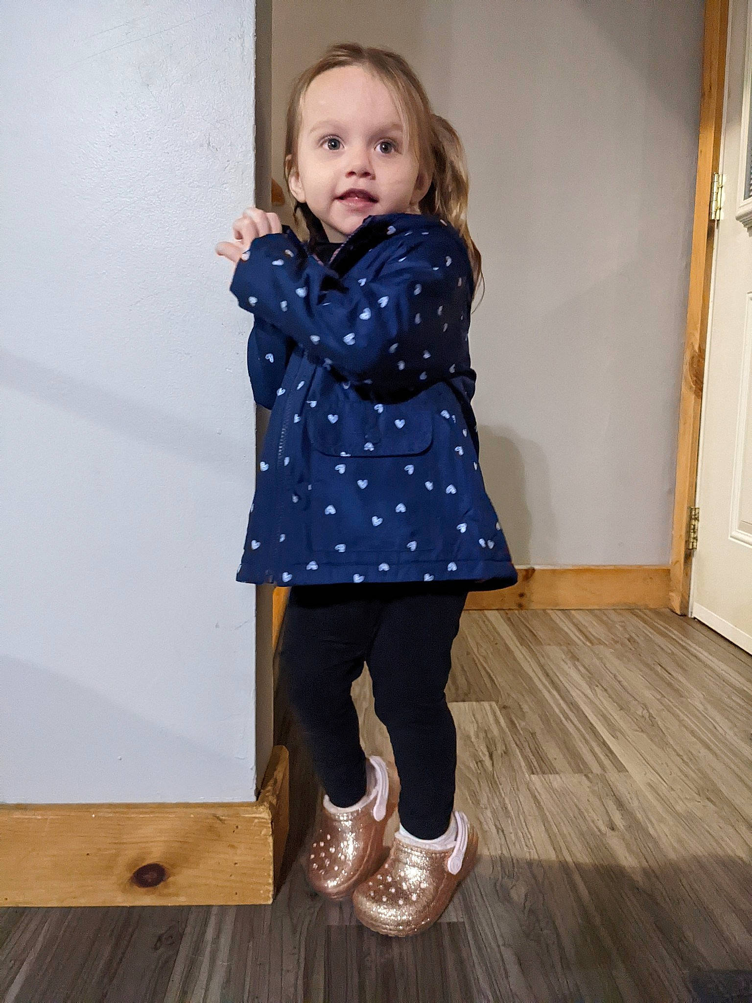 Lillian is registered to the contest to win money with this photo: baby_toddler_clothing, blond, collar, door, dress, dress_shirt, electric_blue, flooring, hardwood, human_leg, joint, knee, pattern, person, plank, sleeve, standing, toddler, varnish, wood