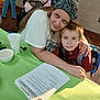 Joshua Leopard joined the competition — help win amazing prizes! woman, boy, child, table, papers, backpack, bandana, indoor, people, embrace, green_tablecloth, cup, document, casual_clothing, portrait, face, expression, friendship, support, event