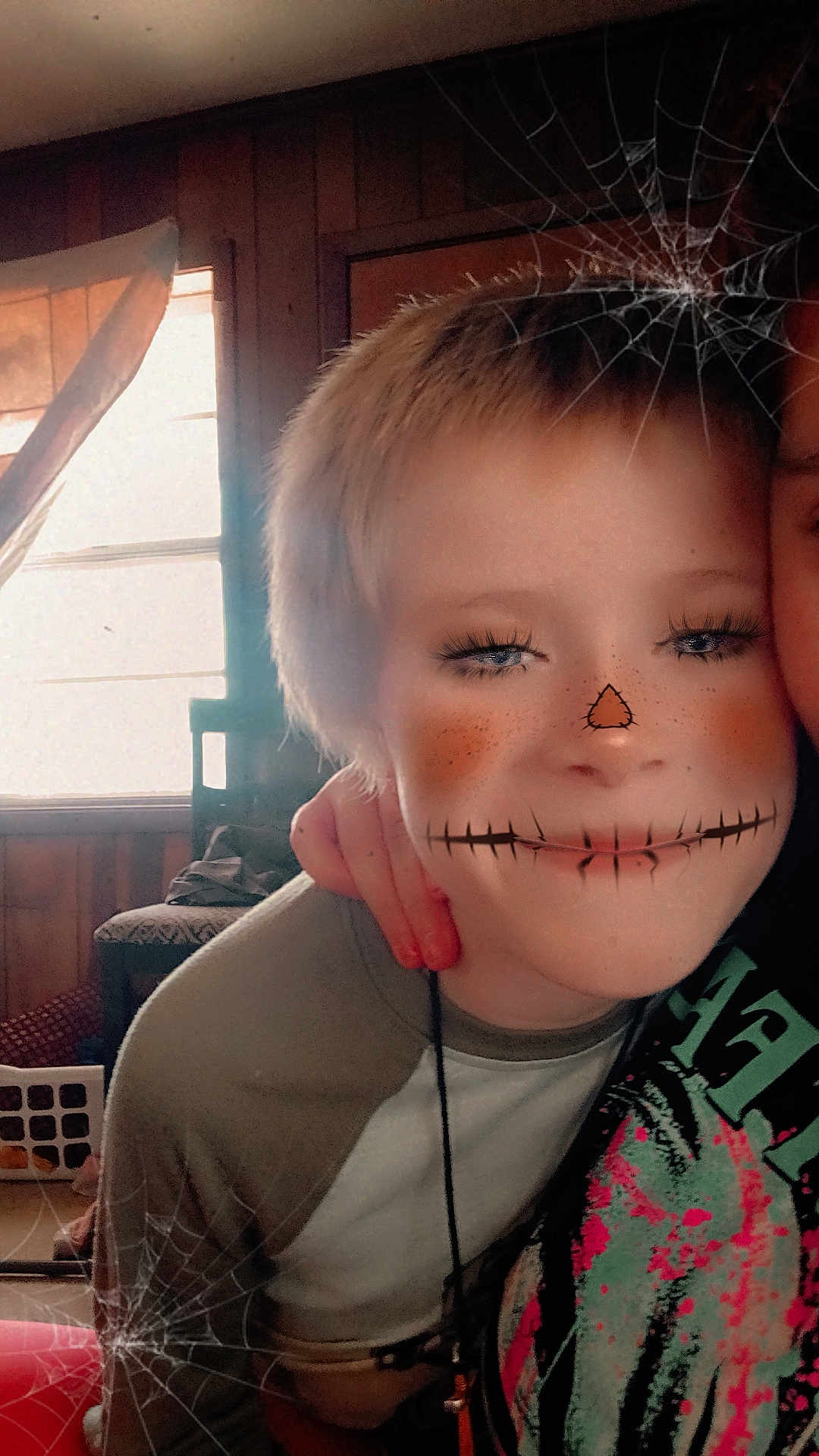 Joshua Leopard joined the competition — help win amazing prizes! child, face_filter, indoor, spooky, halloween, freckles, long_eyelashes, stitched_mouth, triangle_nose, hand, window, curtains, wooden_wall, shirt, person, portrait, smile, spiderweb, casual_clothing, young