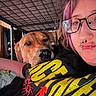 bedroom, black_tshirt, bunk_bed, casual_clothing, closeup, companion, dog, facial_expression, friendship, glasses, indoor, metal_frame, person, pet, piercing, purple_hair, relaxing, resting, selfie, yellow_text