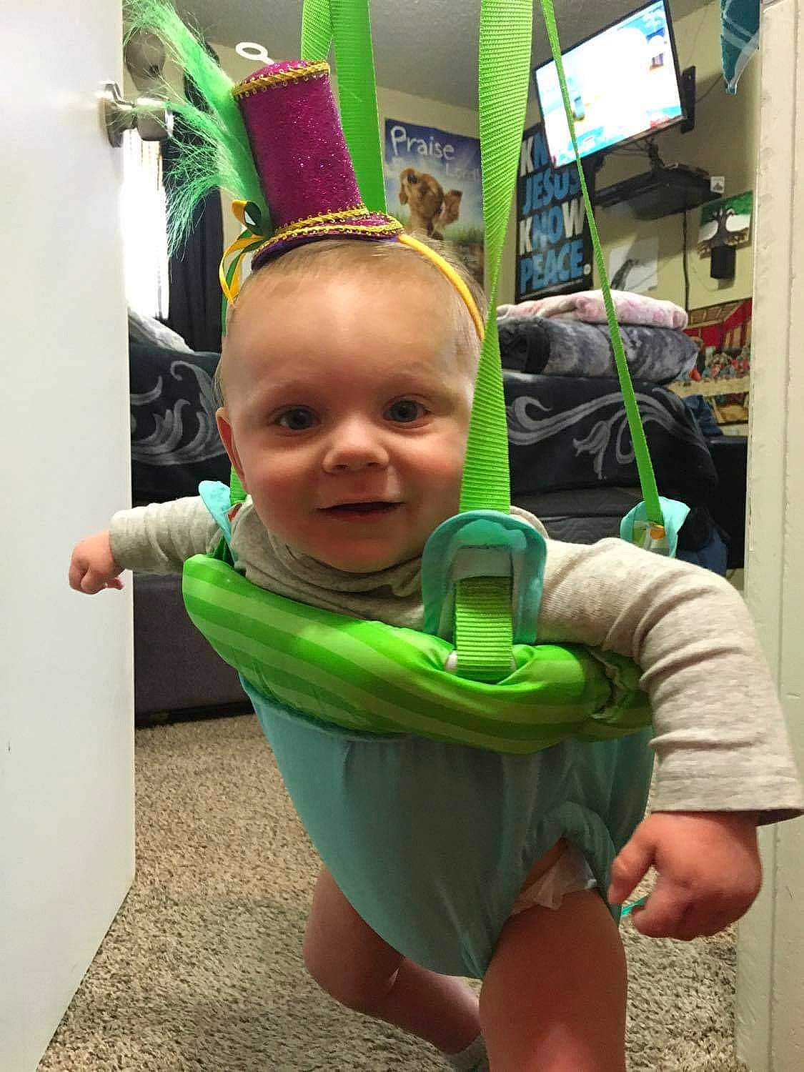 Kain is registered to the contest to win money with this photo: baby, baby_toddler_clothing, child, costume, costume_hat, fictional_character, flooring, fun, green, happy, holiday, joy, party_supply, person, play, room, selfie, smile, t_shirt, television