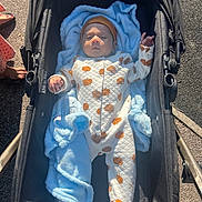 Tejas joined the competition — help win amazing prizes! baby, infant, stroller, blanket, pumpkin_pattern, onesie, outdoor, sunlight, footwear, barefoot, sidewalk, person, clothing, headwear, cute, child, baby_clothes, warm, relaxing, daytime