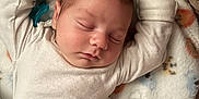 Eli is registered to the contest to win money with this photo: baby, sleeping, blanket, infant, cozy, cute, animal_print, soft_lighting, peaceful, close_up, arms_up, white_clothing, newborn, resting, indoors, child, portrait, comfort, nap_time, toddler