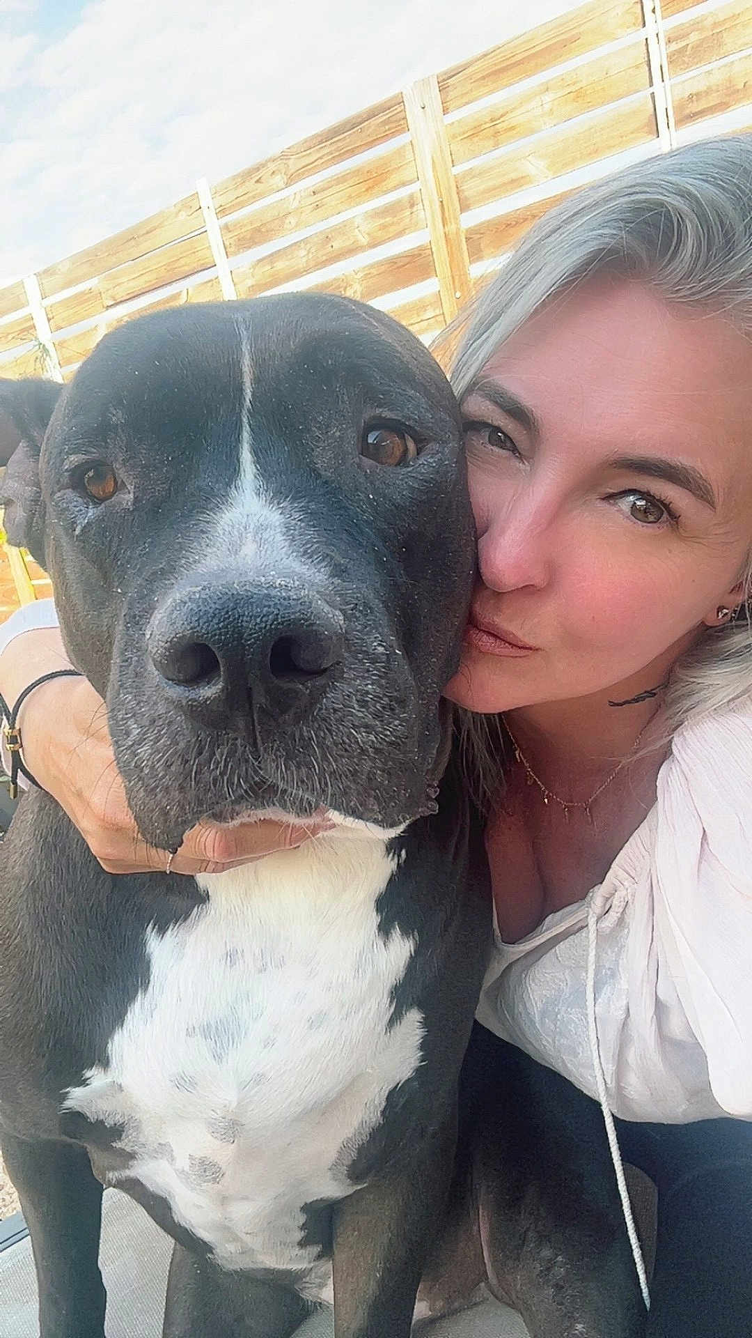 Pitte participe au concours pour gagner de l'argent avec cette photo : dog, woman, selfie, close_up, outdoor, pet, affection, black_and_white, fence, sky, casual_clothing, portrait, face, animal, companion, love, happy, friendship, candid, daylight