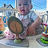 baby, child, infant, toy, activity_center, face, outdoor, blue_sky, house, curious, play, smiling, clothing, hand, plastic, window, daylight, person, seat, expression