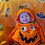 Esmae is registered to the contest to win money with this photo: baby, pumpkin_costume, halloween, carved_pumpkin, orange_blanket, smiling, tongue_out, striped_leggings, cute, holiday, festive, indoor, child, costume, jack_o_lantern, playful, happy, infant, seasonal, celebration