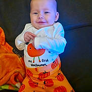 Esmae is registered to the contest to win money with this photo: baby, child, smiling, pajamas, halloween, pumpkins, orange, blanket, couch, cute, festive, holiday, infant, clothing, happy, portrait, indoors, person, sitting, face