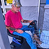 Pee Wee joined the competition — help win amazing prizes! man, dog, mobility_scooter, pet_carrier, basket, camouflage_cap, pink_shirt, blue_jeans, sneakers, mustache, tattoos, outdoor, entrance, door, warning_sign, brick_wall, shopping_cart, seated, small_dog, transportation