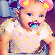 Bailey is registered to the contest to win money with this photo: baby, toddler, pacifier, headband, bow, high_chair, child, face, blue_eyes, hands, clothing, pink, white_shirt, patterned_outfit, indoor, digital_filter, cute, infant, playful, portrait