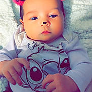 Sophia is registered to the contest to win money with this photo: baby, blanket, cartoon_print, child, clothing, cozy, cute, face, filter, floral_pants, hands, indoor, infant, lying_down, nose, person, pink_ears, portrait, soft, young