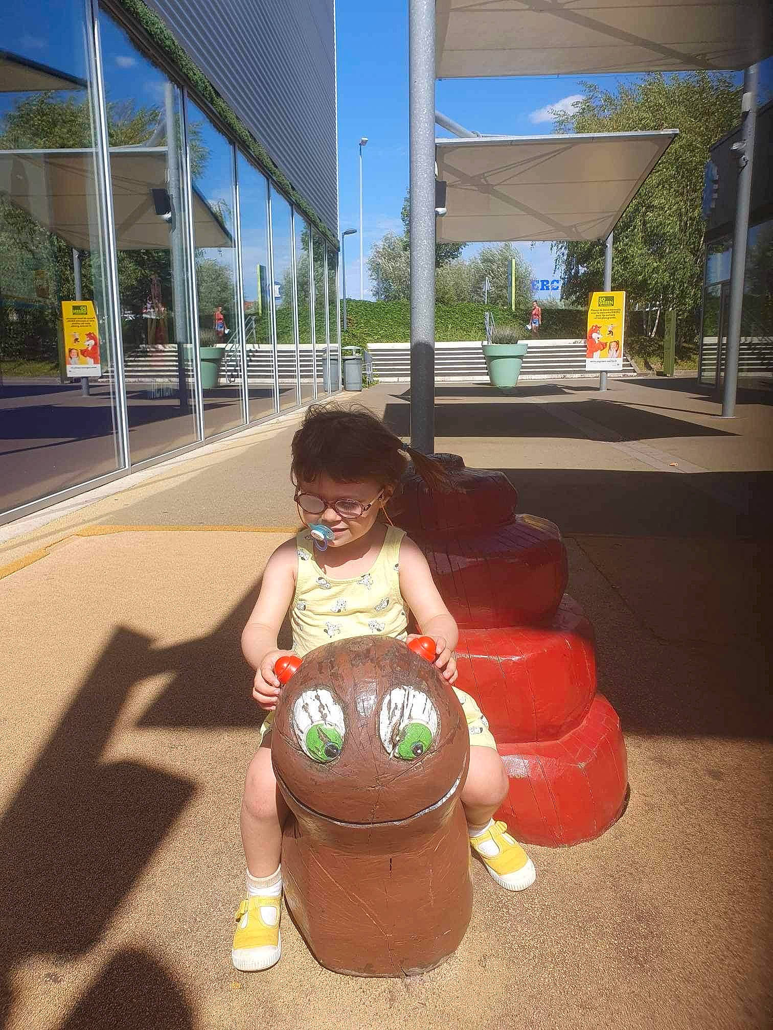 Maëlya a rejoint le concours — aidez-le/la à gagner de superbes lots ! asphalt, brassiere, building, city, eyewear, flooring, fun, hat, human_leg, leisure, lighting, person, public_space, recreation, sitting, sky, sunglasses, swimwear, thigh, toddler