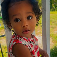 Nova joined the competition — help win amazing prizes! child, toddler, girl, portrait, curly_hair, hair_buns, brown_eyes, looking_at_camera, serious_expression, floral_dress, red_dress, standing, outdoor, porch, window, greenery, sunlight, close_up, photography, family_photo