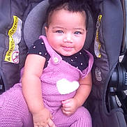 Kaylani joined the competition — help win amazing prizes! baby, child, car_seat, knitted_clothing, purple_outfit, heart_design, bow, smile, face, hand, arm, infant, cute, seated, black_shirt, polka_dot, indoors, warning_label, safety, person