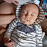 baby, sleeping, hoodie, striped_clothing, whale_design, hand, face, closed_eyes, indoor, living_room, bookshelf, furniture, couch, blanket, person, child, relaxed, cute, peaceful, infant