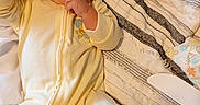 Anthony joined the competition — help win amazing prizes! baby, infant, yellow_onesie, blanket, bed, thumb_sucking, face, cute, child, sleepwear, fabric, texture, hand, lying_down, cozy, soft_lighting, person, indoors, comfort, youth