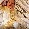 baby, infant, yellow_onesie, blanket, bed, thumb_sucking, face, cute, child, sleepwear, fabric, texture, hand, lying_down, cozy, soft_lighting, person, indoors, comfort, youth