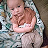 Anthony is registered to the contest to win money with this photo: baby, child, blanket, dinosaur_pattern, brown_shirt, striped_pants, indoor, couch, cozy, curious, person, infant, young_child, hands, feet, portrait, comfortable, soft_texture, seated, looking