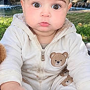 Sanad Elharmouchi is registered to the contest to win money with this photo: baby, child, close_up, face, garden, greenery, hands, hoodie, infant, jumpsuit, outdoors, portrait, serious_expression, sitting, socks, stream, teddy_bear, waterfall, white_clothing, wide_eyed
