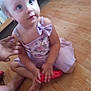 Freyja is registered to the contest to win money with this photo: child, toddler, dress, bow, floor, wooden_floor, toy, hand, barefoot, sitting, indoor, person, skin, face, blue_eyes, cute, young, small, holding, pink