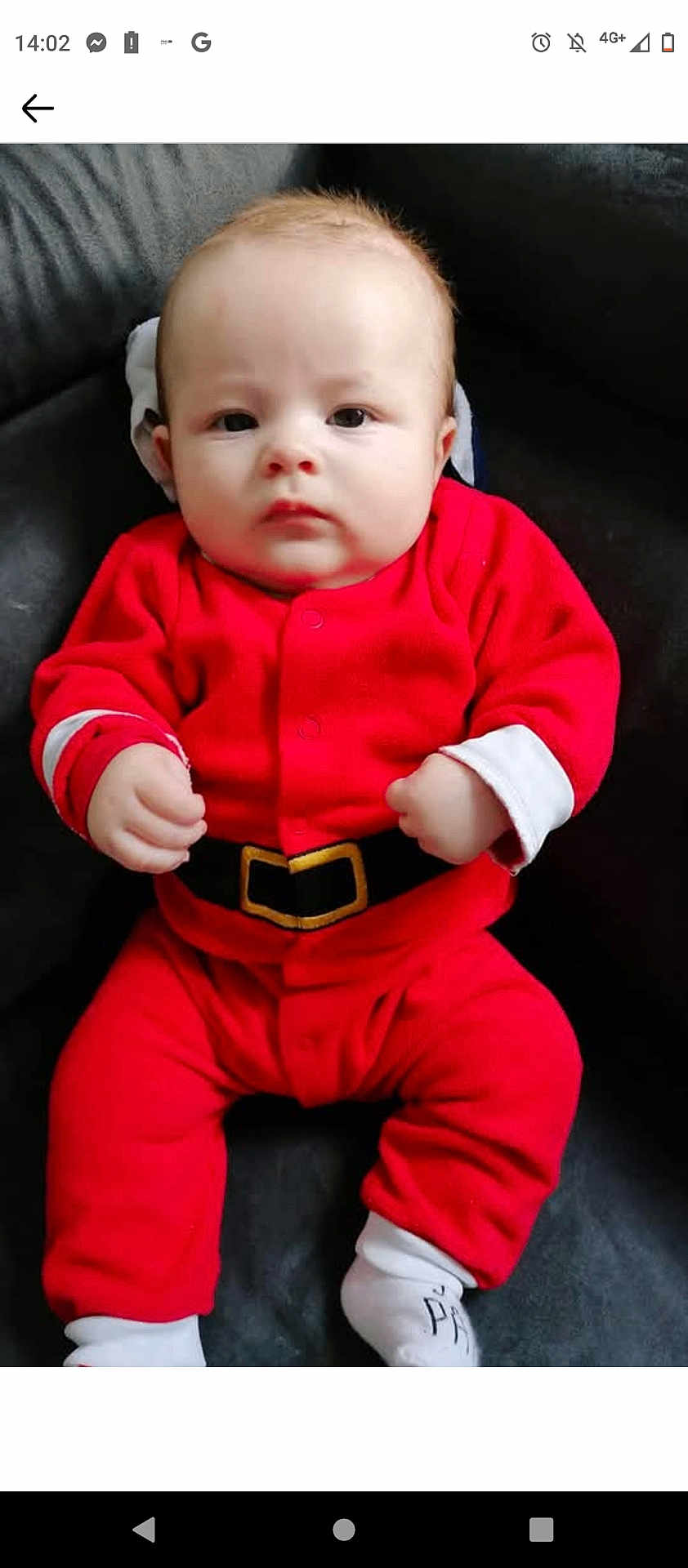 Gabriel participe au concours pour gagner de l'argent avec cette photo : baby, infant, red_clothing, santa_outfit, face, hands, socks, seated, indoor, cute, portrait, child, young, holiday, festive, expressionless, furniture, couch, soft_lighting, casual