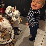 Gabriel a rejoint le concours — aidez-le/la à gagner de superbes lots ! toddler, child, striped_shirt, indoor, tile_floor, plush_toy, holiday_decoration, santa_claus, doll, winter_clothing, smiling, motion_blur, face, person, toy, home, floor, cute, decor, playful