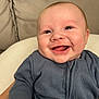 Mylo is registered to the contest to win money with this photo: baby, smile, happy, infant, blue_clothing, face, skin, eyes, person, child, cute, portrait, closeup, human, young, indoors, soft_background, sitting, warm, joy
