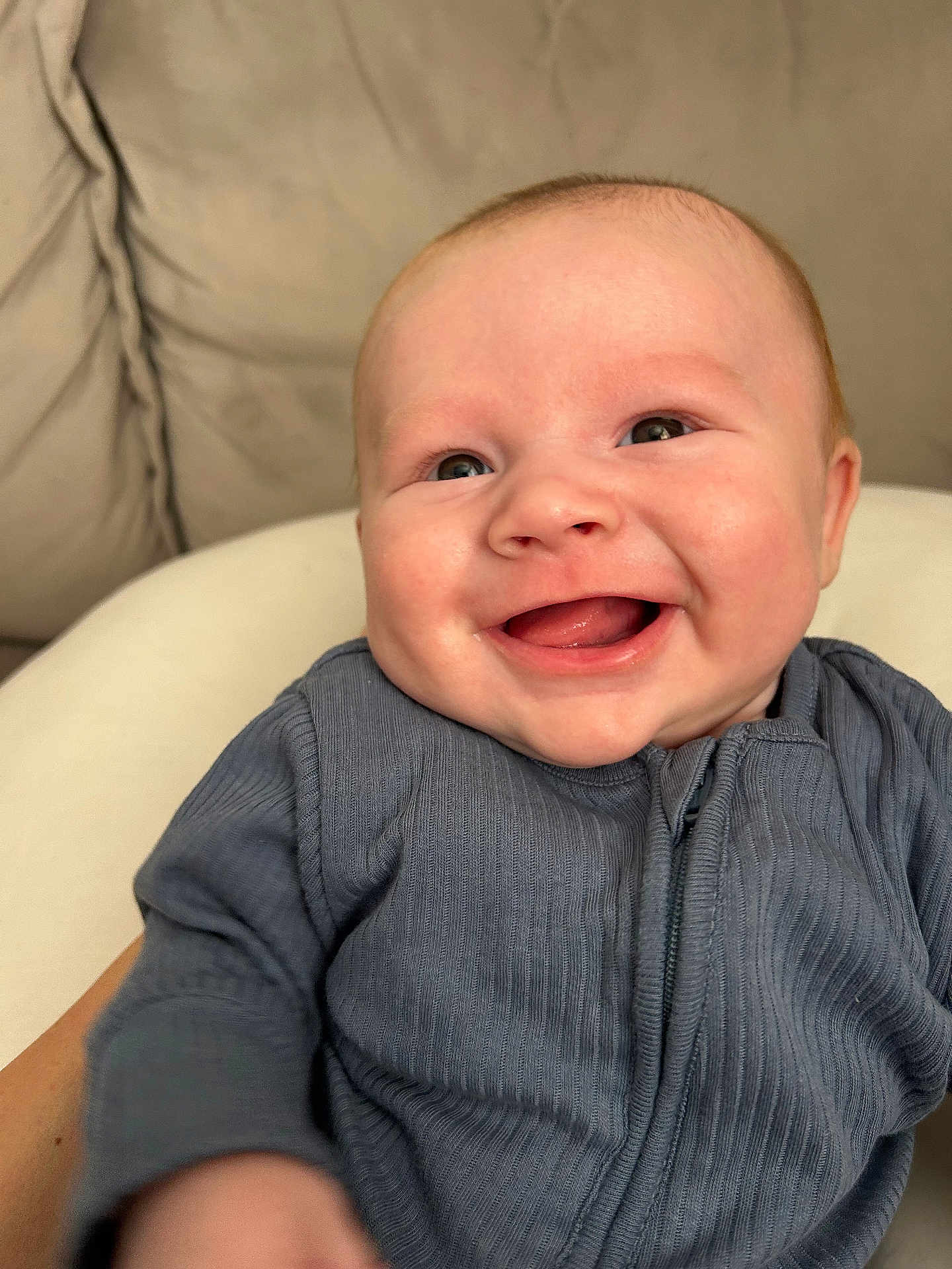 Mylo is registered to the contest to win money with this photo: baby, smile, happy, infant, blue_clothing, face, skin, eyes, person, child, cute, portrait, closeup, human, young, indoors, soft_background, sitting, warm, joy