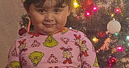 Amelia joined the competition — help win amazing prizes! child, pajamas, grinch, christmas_tree, holiday_lights, water_bottle, smile, indoor, festive, decorations, holiday, cute, person, young_child, celebration, christmas, lighting, standing, hair_clips, fun