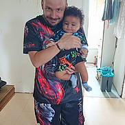Aaron participe au concours pour gagner de l'argent avec cette photo : man, baby, child, indoor, smiling, holding, colorful_clothing, socks, shorts, tshirt, floor, doorway, cleaning_supplies, mop, bucket, curly_hair, facial_hair, person, home, casual