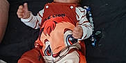 Aaron participe au concours pour gagner de l'argent avec cette photo : baby, infant, child, bed, blanket, plush_toy, disney, clothing, smiling, thumbs_up, curly_hair, lying_down, cute, comfortable, indoor, soft_toys, person, footwear, striped_sleeves, colorful_outfit
