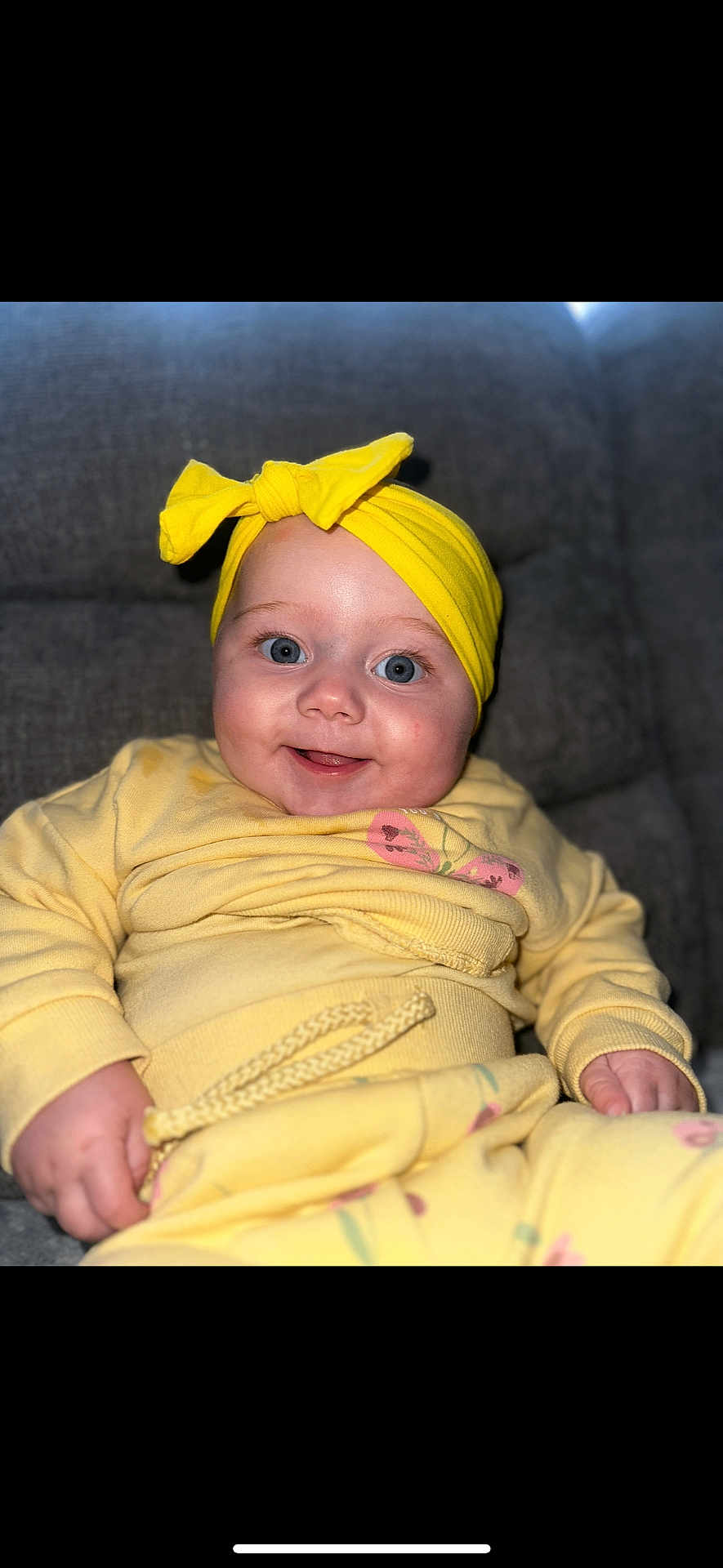 Kyla joined the competition — help win amazing prizes! baby, child, smiling, yellow_clothing, headband, bow, blue_eyes, couch, indoor, portrait, happy, infant, closeup, soft_fabric, sitting, cute, person, cozy, comfortable, casual_wear