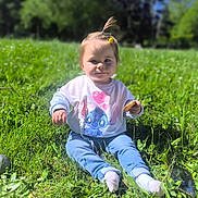 Luna a rejoint le concours — aidez-le/la à gagner de superbes lots ! blue_sky, casual_clothing, child, cookie, cute, daylight, flower, grass, greenery, hair_tie, happy, nature, outdoor, person, playful, sitting, smiling, sunlight, sweatshirt, toddler