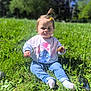 blue_sky, casual_clothing, child, cookie, cute, daylight, flower, grass, greenery, hair_tie, happy, nature, outdoor, person, playful, sitting, smiling, sunlight, sweatshirt, toddler