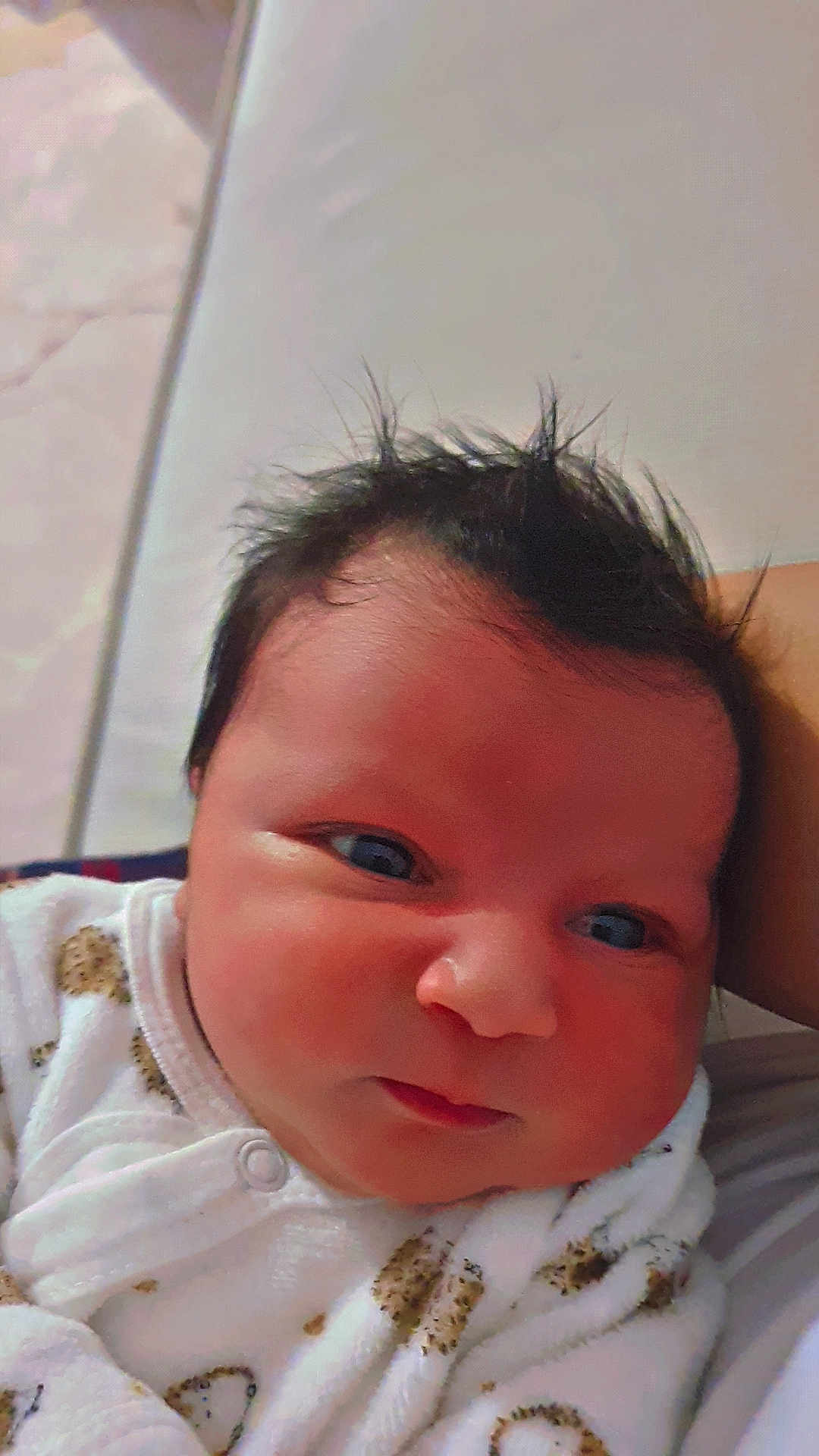 Layth a rejoint le concours — aidez-le/la à gagner de superbes lots ! baby, infant, face, hair, eyes, skin, clothing, white_outfit, patterned_clothing, closeup, cute, newborn, portrait, lying_down, soft, child, indoors, expression, head, young