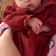 Aëla a rejoint le concours — aidez-le/la à gagner de superbes lots ! baby, infant, child, pigtails, red_dress, pink_blanket, adult_hand, face, portrait, indoor, adorable, sleepy, cheeks, eyes, person, cozy, clothing, closeup, sitting, lap