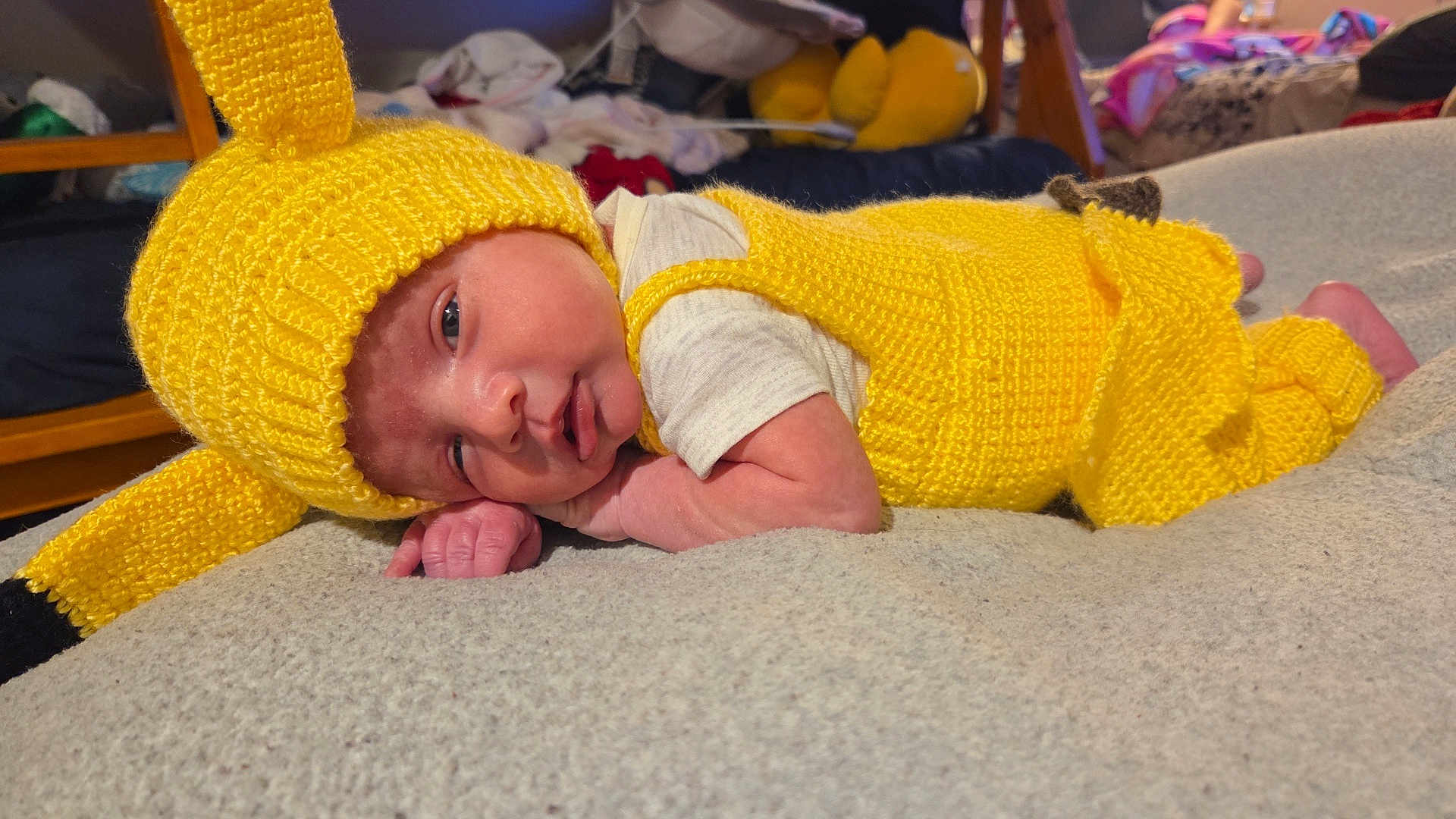 Caspian joined the competition — help win amazing prizes! baby, infant, yellow_knit, knitted_hat, knitted_outfit, lying_down, soft_surface, cute, small_hands, face, indoors, cozy, colorful_background, child, newborn, portrait, sleepy, resting, warm_clothing, closeup